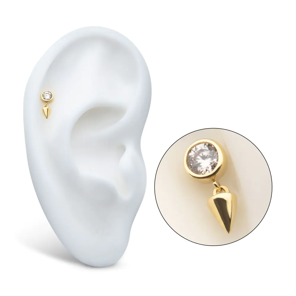 A 14k gold bezel-set swarovski crystal with a spike dangle, shown on display in a model ear.