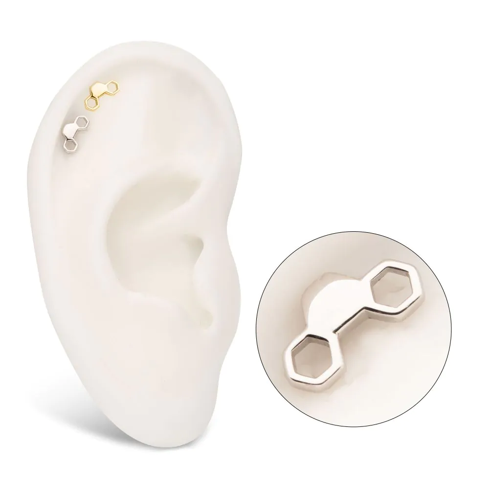 Two of the same honeycomb earrings, one in silver colour and one in gold, installed in two helix piercings of a model ear.