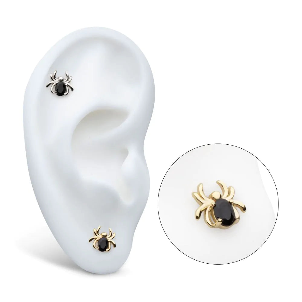 A silver and gold version of a spider earring on display on a model ear, with a close-up shot as well.