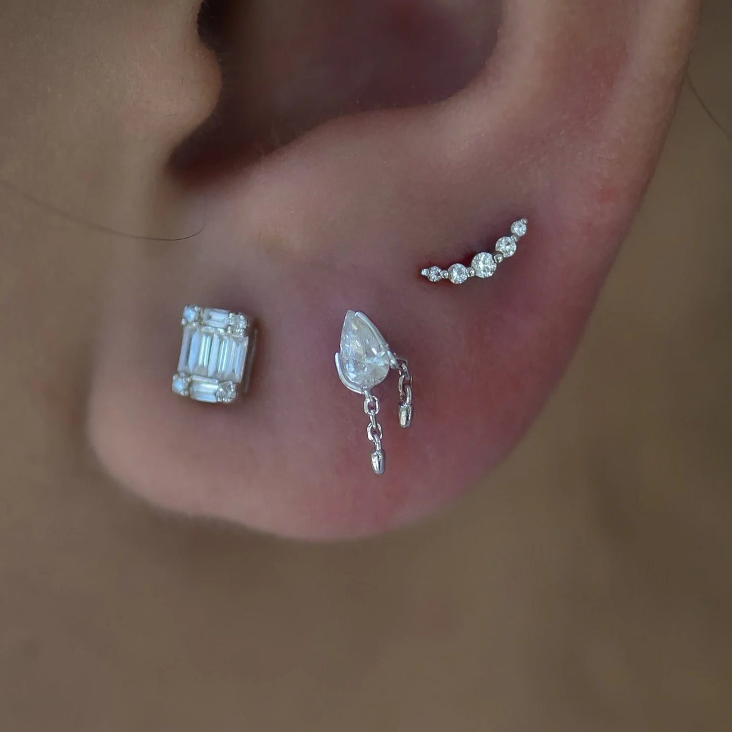 Close-up of an ear with several earrings in it.