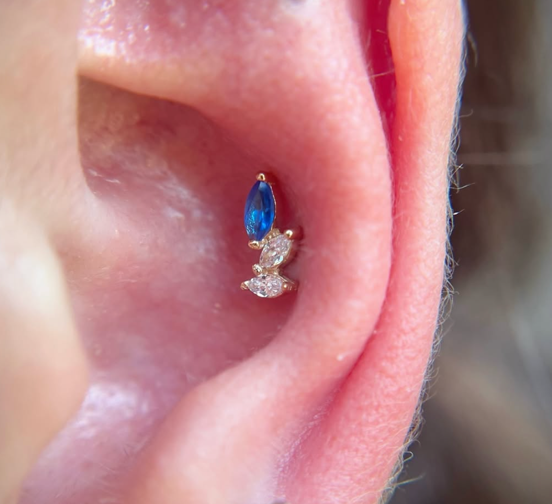 A close of an ear with a piece of jewelry in a conch piercing.
