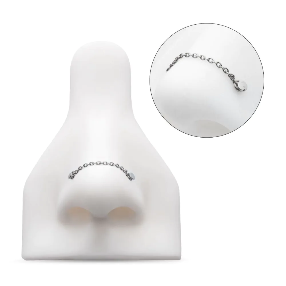 A rolo chain, in silver colour, shown on a model nose connecting two piercings on either side of the nose.