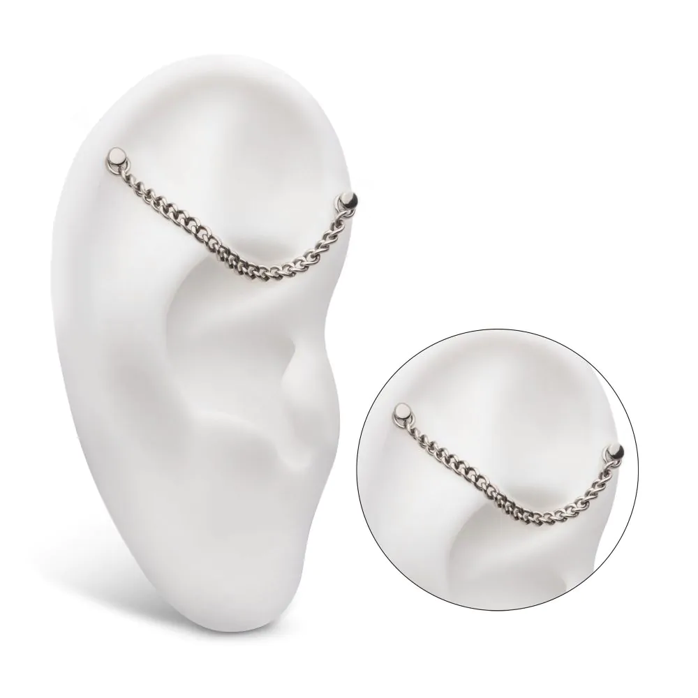 A curb chain in silver colour shown in a model ear connecting two different piercings.