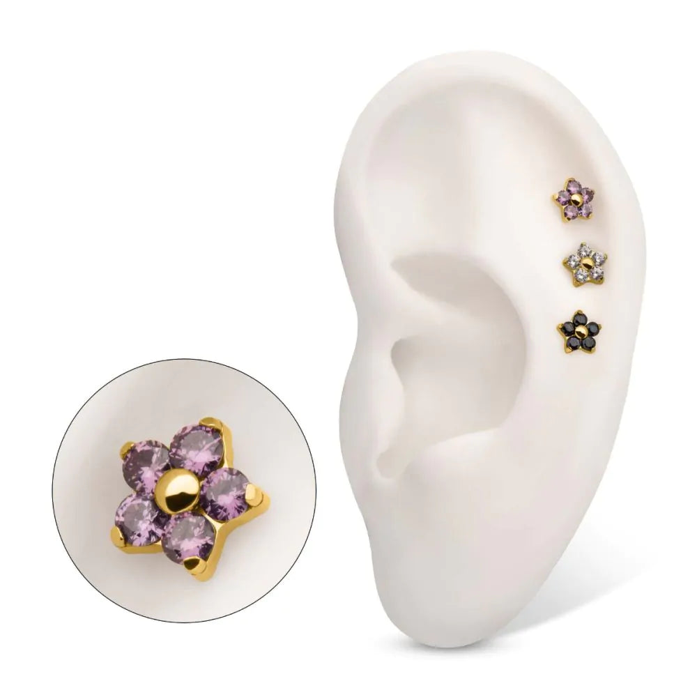 A model ear displays several of the same pieces of flower-shaped jewelry in various colours.