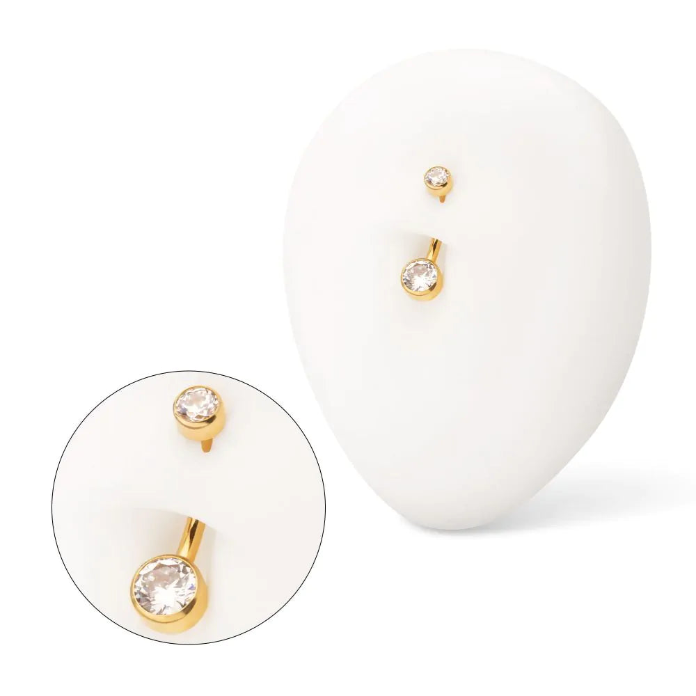 A gold-coloured navel barbell displayed in a white navel model.