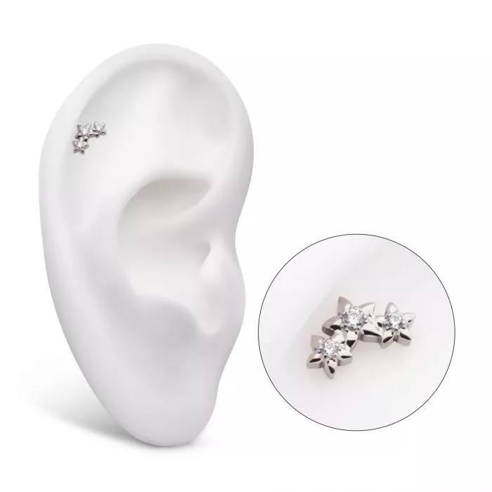 A triple-star earring with three Swarovski crystals, shown on display in the helix piercing of a model ear.